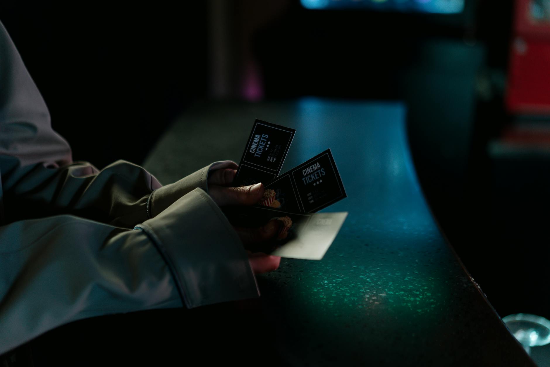 Moody image of a person holding cinema tickets at night, highlighting anticipation of a movie night.