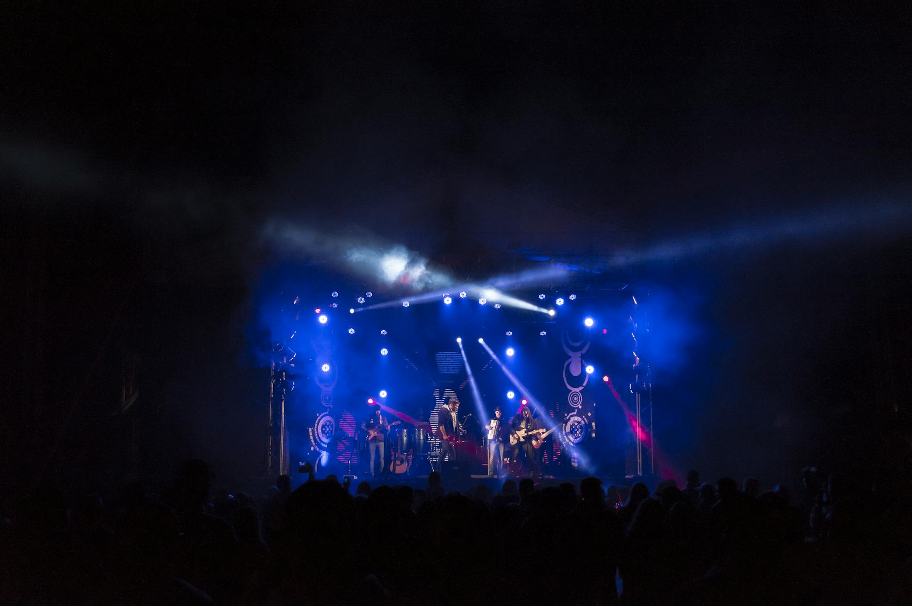 High-energy band performance on a stage with colorful lights and an engaged crowd.