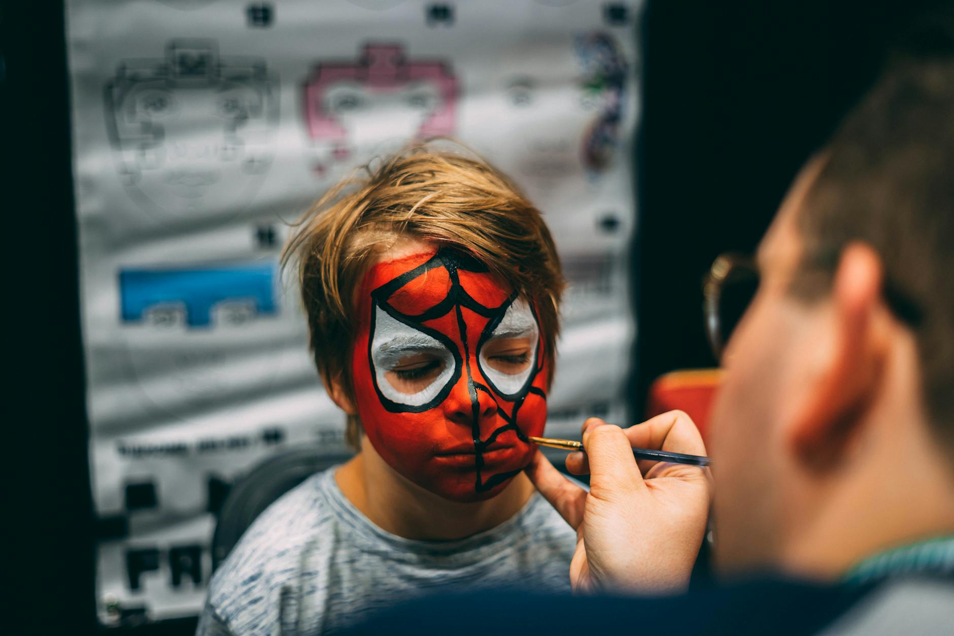 A child enjoys festival face painting with a bold Spider-Man design.