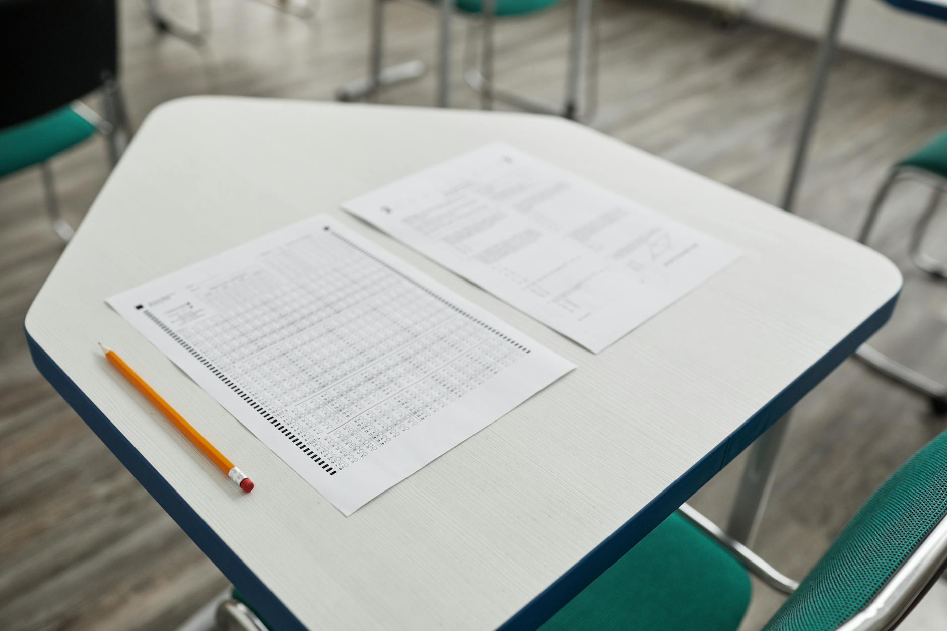 A close-up image of an exam paper and pencil on a classroom desk, ready for a test.