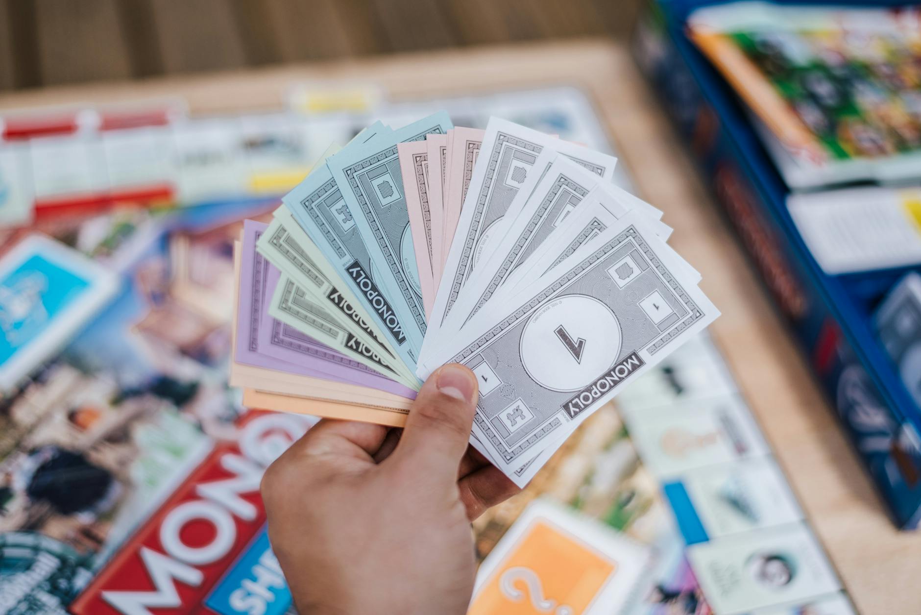 Close-up of Monopoly money held during a board game session, with blurred background.