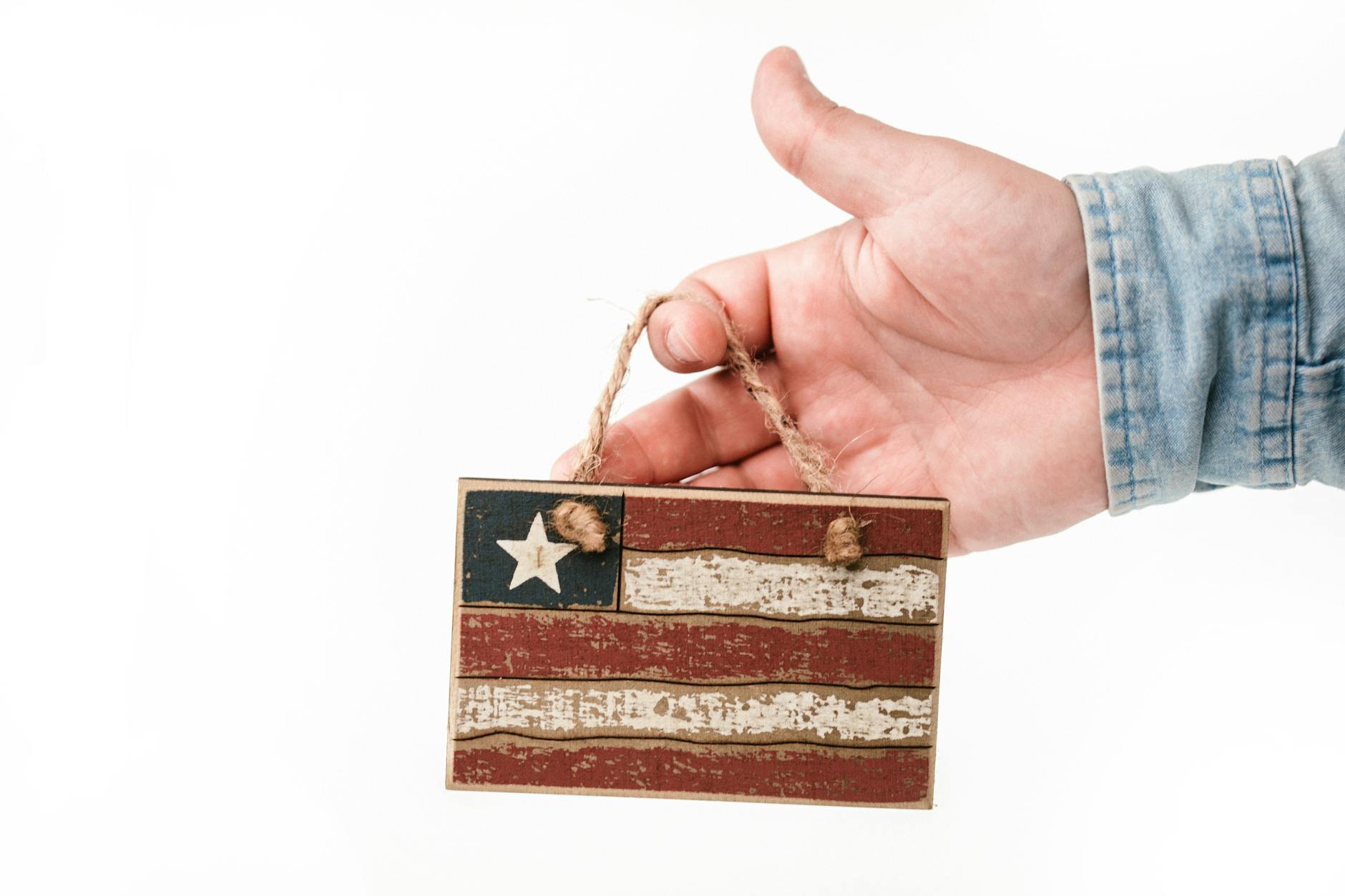 Close-up of a hand holding a rustic American flag decoration symbolizing patriotism.
