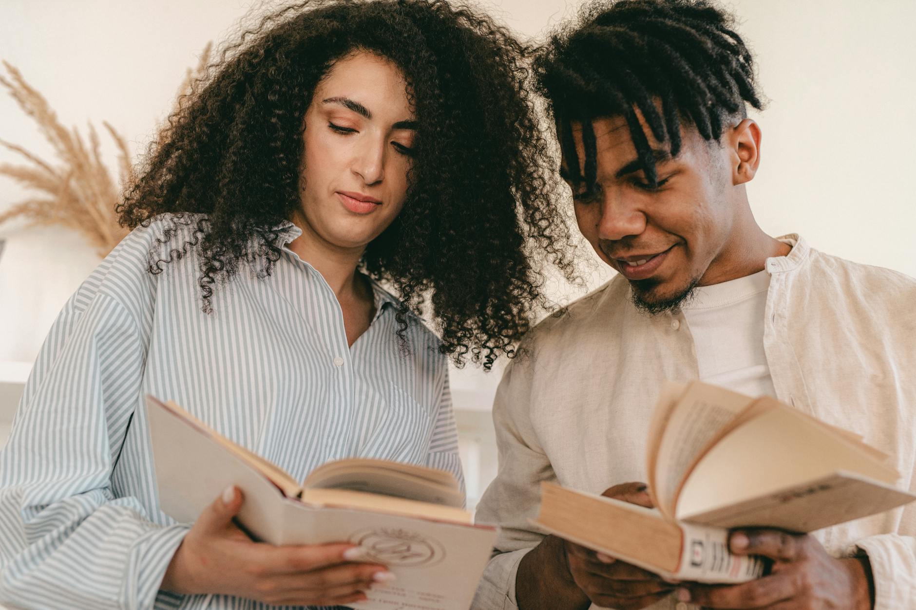 A young couple enjoying books indoors, promoting a love for reading and diversity.