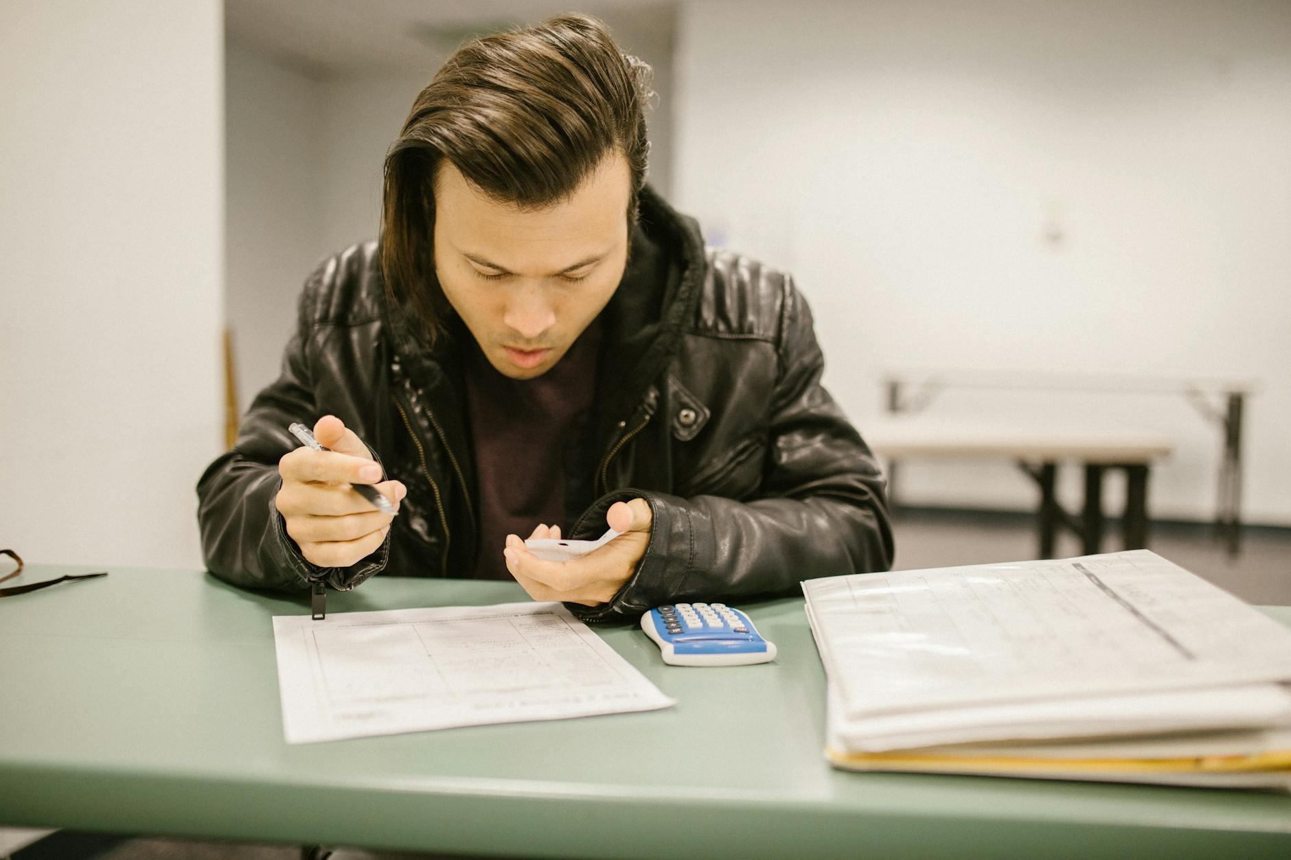 A male student in a classroom studying for an exam with a focus on his notes.