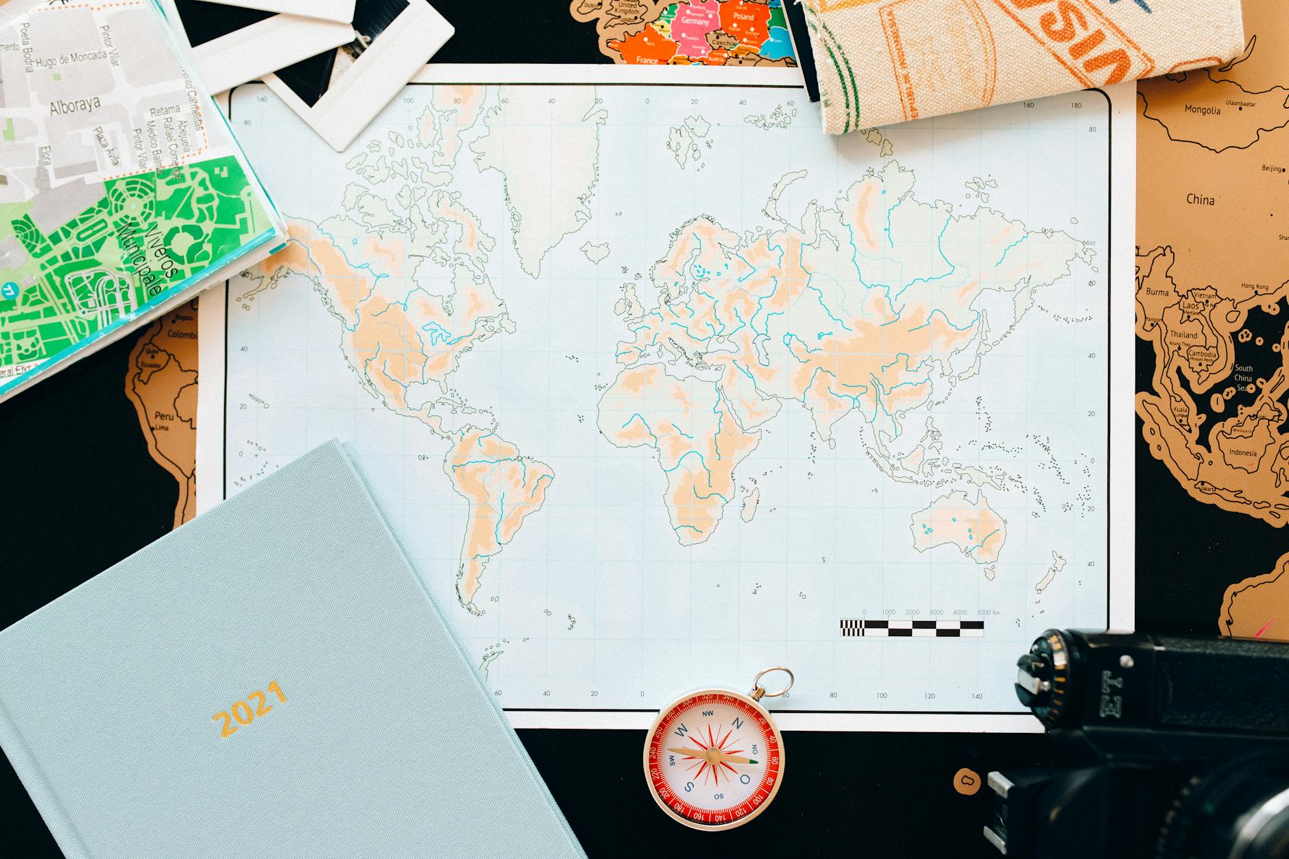 Flat lay of travel essentials including a world map, compass, and planner, perfect for planning your next adventure.