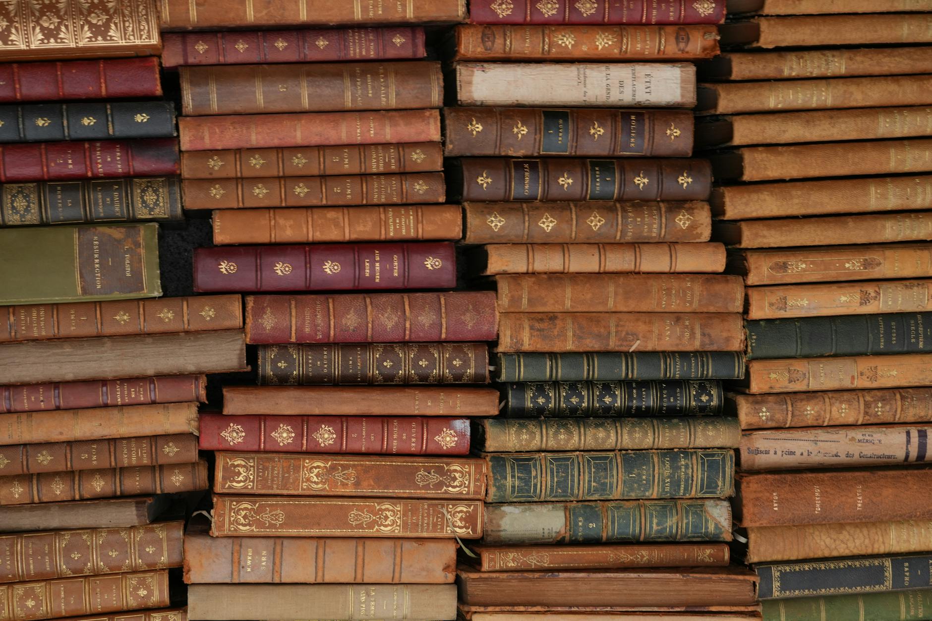 Stack of vintage leather-bound books with ornate designs, reflecting history and literature.