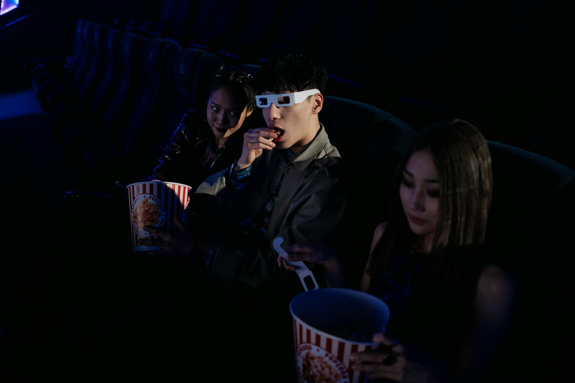 A group of young adults enjoying a movie at the cinema, complete with popcorn and 3D glasses.