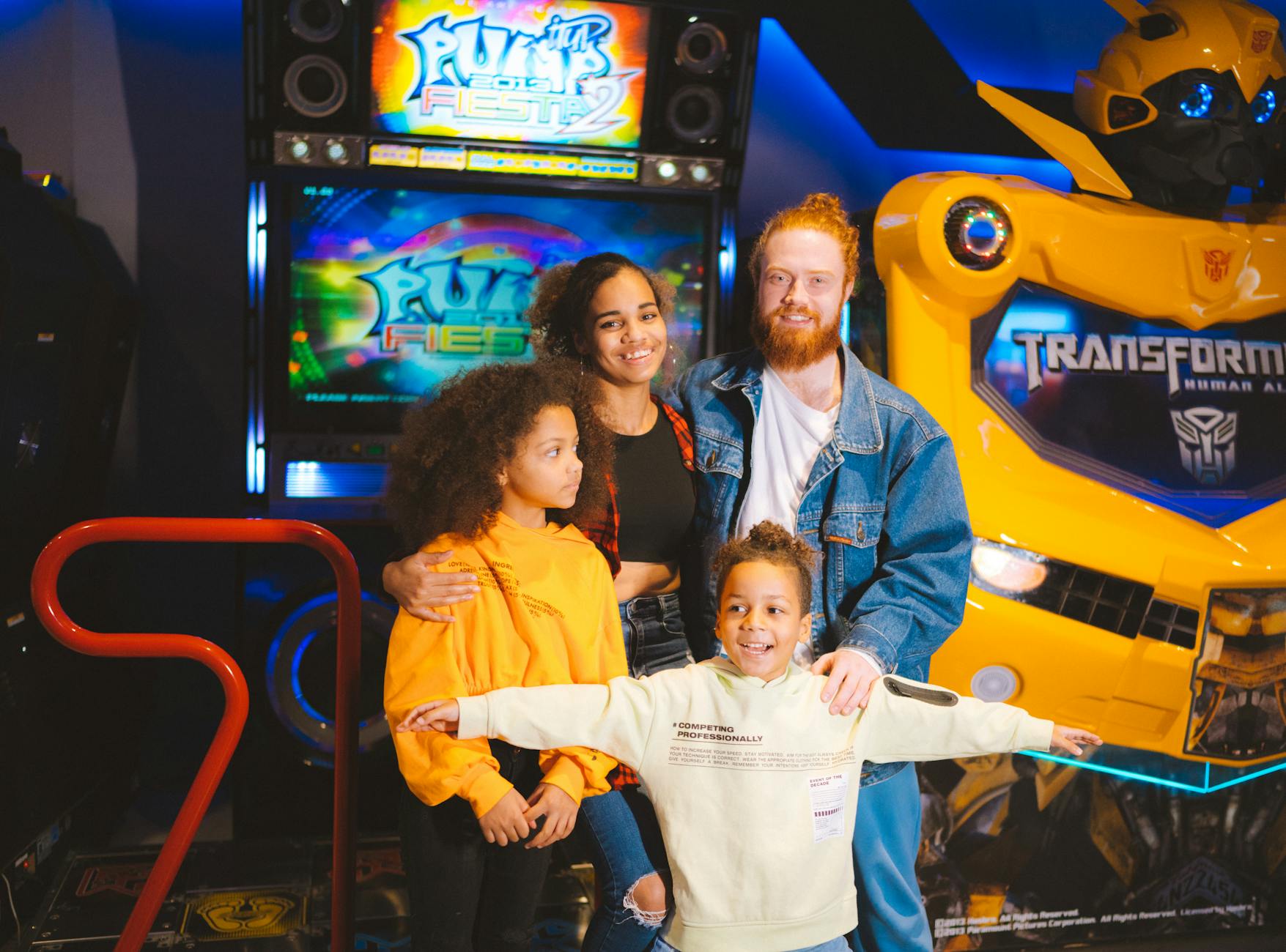 A cheerful family posing with arcade games and robots, capturing a vibrant amusement moment.