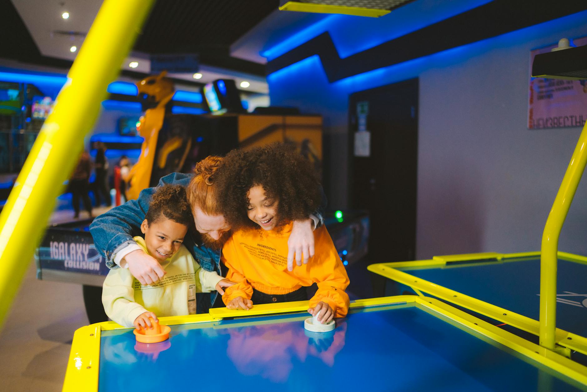Family having fun playing air hockey together at an arcade. Happy moments and smiles captured.