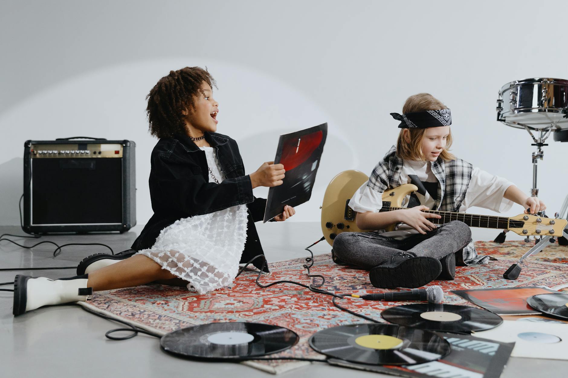 Two kids having fun with musical instruments and vinyl records indoors.