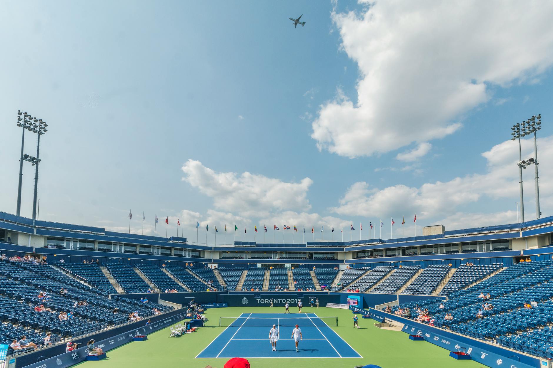 Dynamic tennis match in progress at an outdoor stadium in Toronto 2015 event, with vibrant sky and audience.