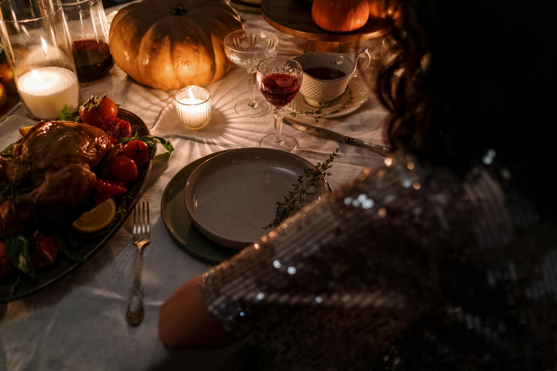Intimate Thanksgiving dinner setup with candles, turkey, and elegant table setting.