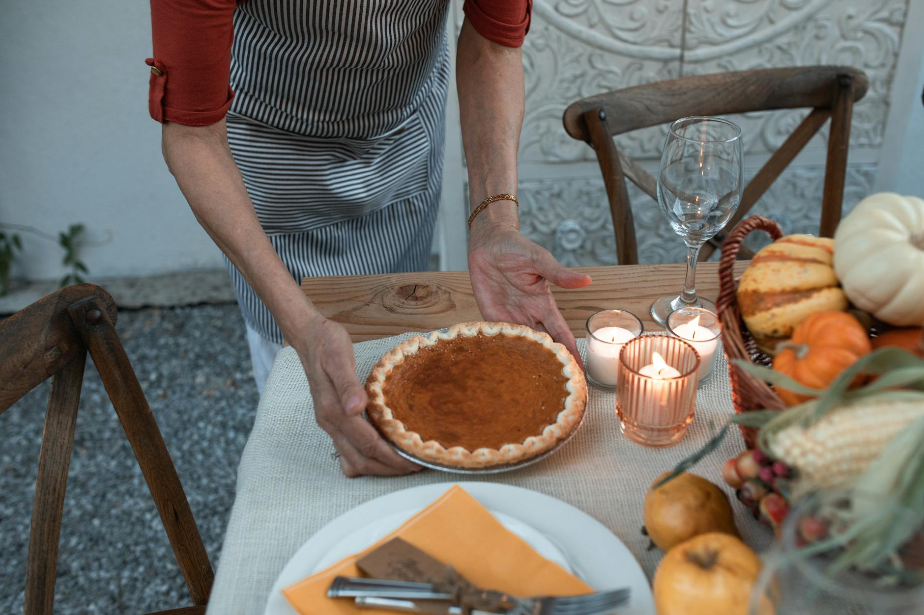 A cozy Thanksgiving table setting featuring a homemade pumpkin pie amidst autumn decor.